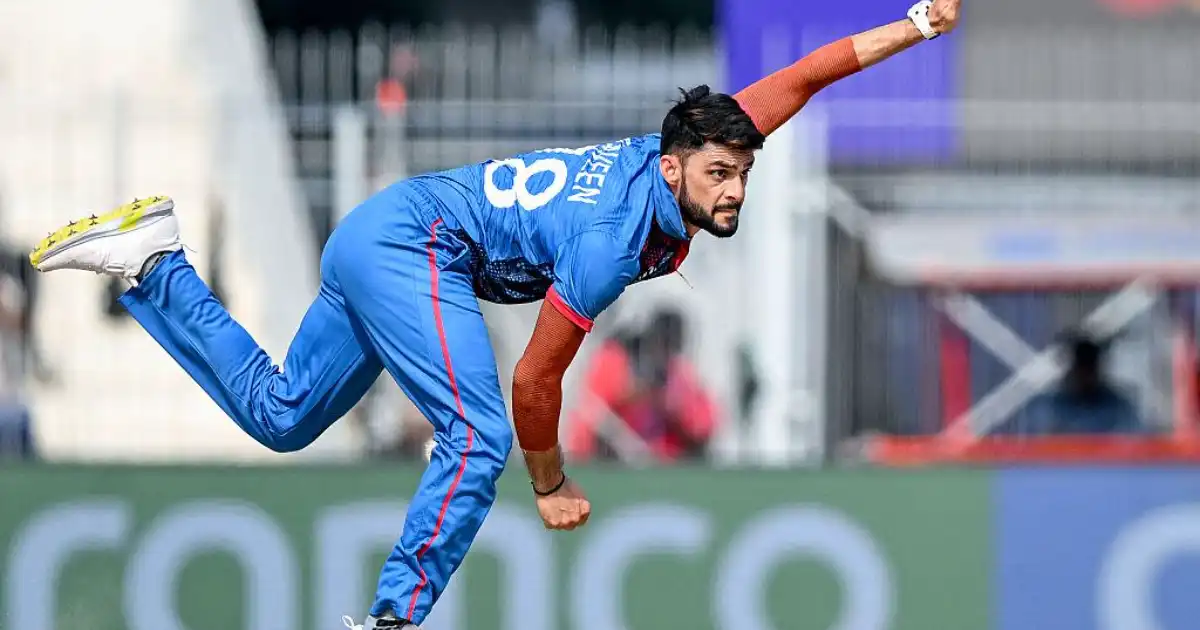 Naveen-ul-Haq delivering the ball in Afghanistan's blue uniform during an international cricket match.